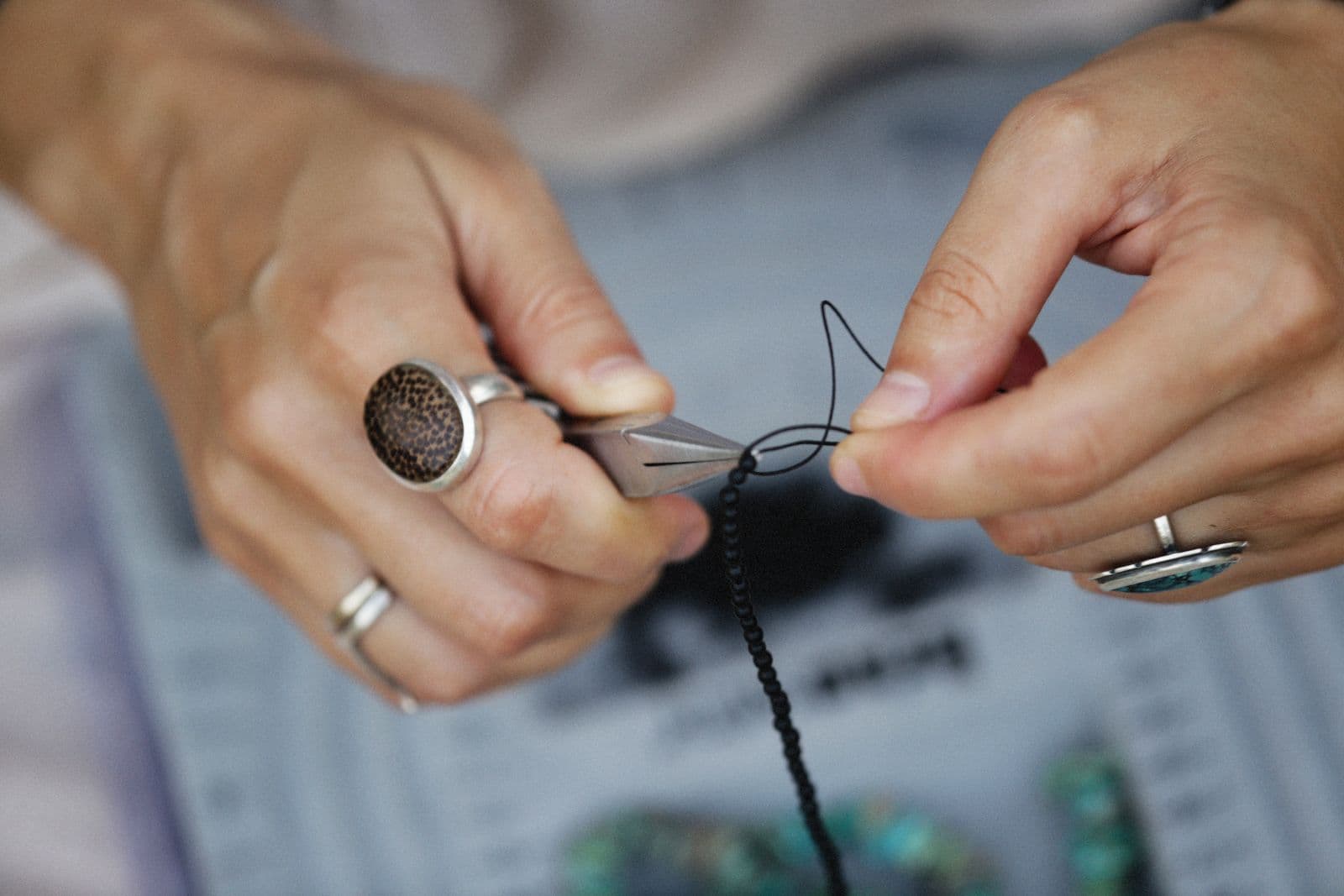 Hands patiently threading beads into a handmade piece